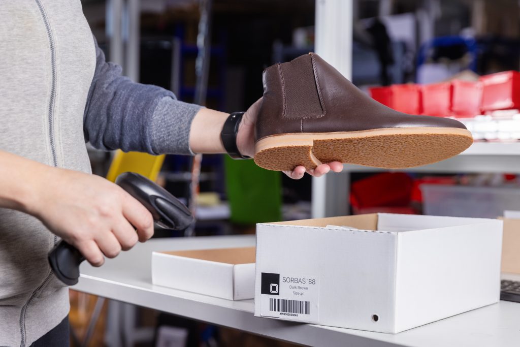 Mitarbeiter scannt einen Schuh vor dem Verpacken