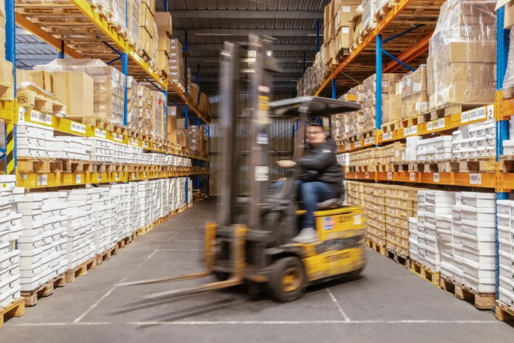 Mitarbeiter mit Stapler im Lager